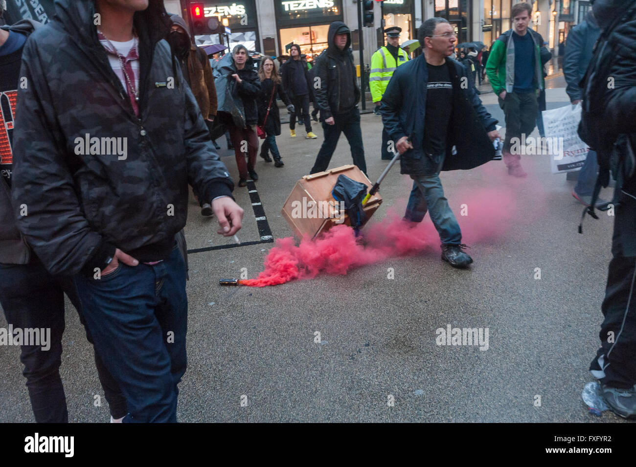 Londra, Regno Unito. Il 15 aprile, 2016. Una svasatura rossa spicca il fumo nel centro di Oxford Circus a marzo al led mediante azione diretta gruppo strade arriva da cucina. Il mese di marzo sotto la pioggia intorno al centro di Londra è stato in solidarietà con la London crescente della comunità senzatetto e chiesto un'azione da parte del governo e dei consigli per terminare le loro politiche che rendono le persone senza tetto e a porre fine alla criminalizzazione dei senzatetto. I dimostranti hanno portato tende, sacchi a pelo e cibo che intendono aderire al uccidere l'alloggiamento Bill sleepout a Southwark e raccolto donazioni. Peter Marshall / Alamy Live News Foto Stock