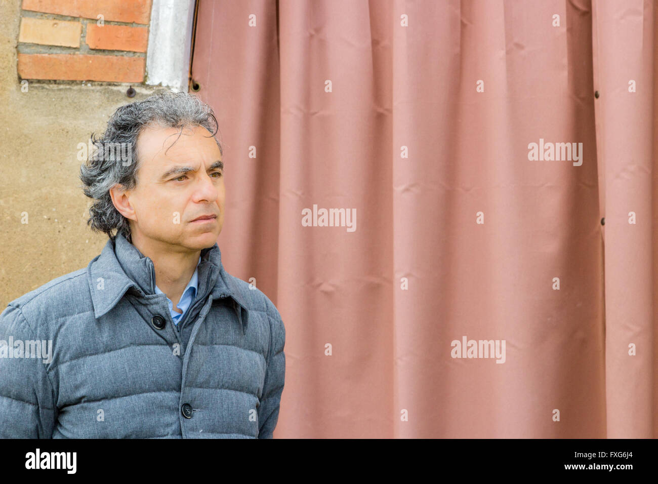 La classe uomo in giacca grigia premurosamente davanti a un sipario rosso Foto Stock