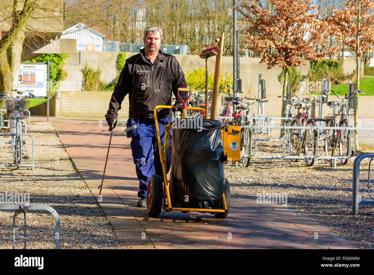 Lund, Svezia - 11 Aprile 2016: il lavoro uomo a camminare verso di voi con la garbage carrello e strumento per prelevare i rifiuti dalla strada. Un Foto Stock