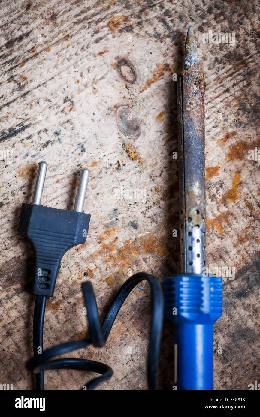 Immagine a colori di un saldatore elettrico su un asse di legno. Foto Stock