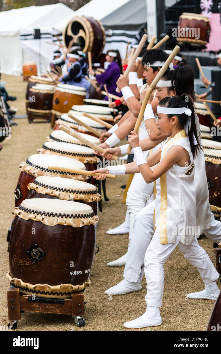 Taiko batteristi, Kumi-daiko concerto. Vista laterale della fila di bambini e adolescenti in tradizionale costume drumming, battendo la linea di nagado-daiko tamburi. Foto Stock