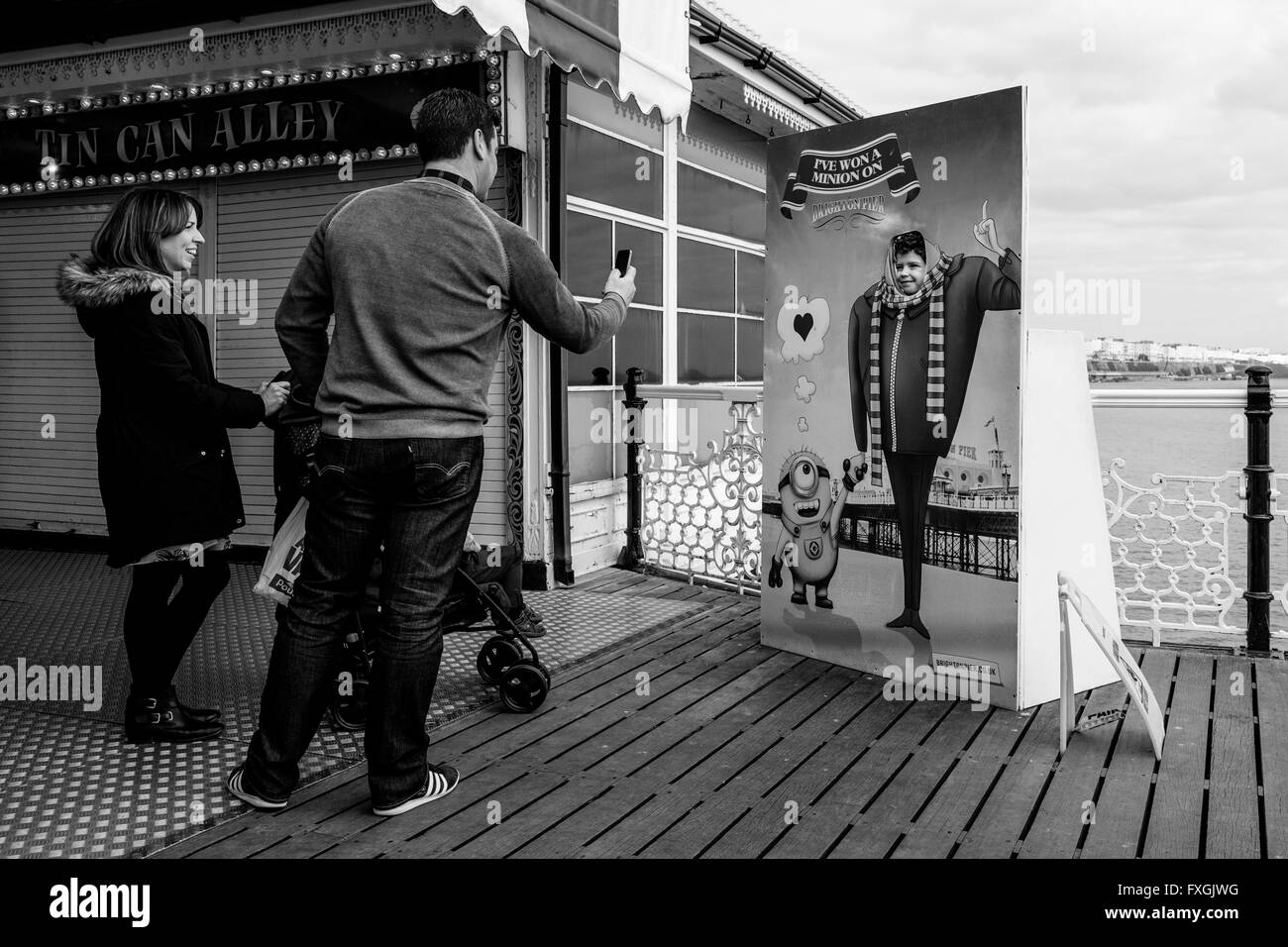 Una famiglia comportano per le foto in corrispondenza di una faccia tagliata schede fotografiche, Brighton Pier, Sussex, Regno Unito Foto Stock