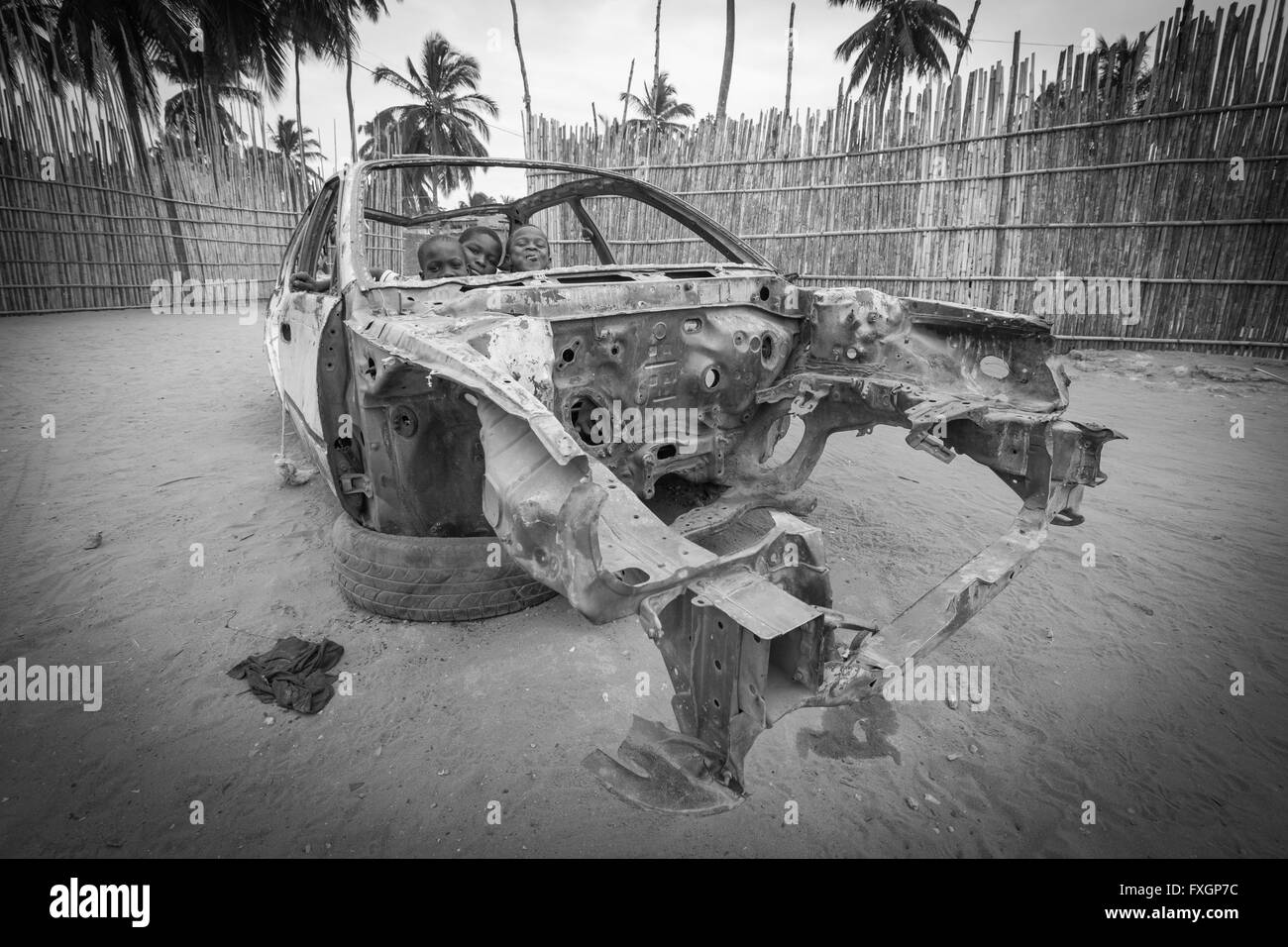 Mozambico, bambini che giocano in un'auto danneggiata e in bianco e nero. Foto Stock