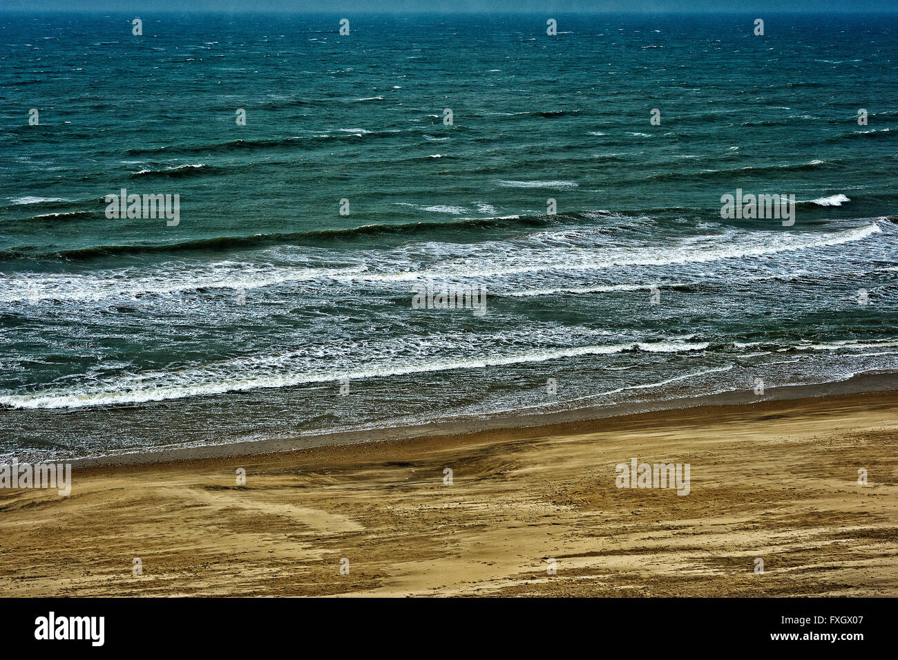 Ventoso inverno spiaggia con sabbia soffiata e surf Foto Stock
