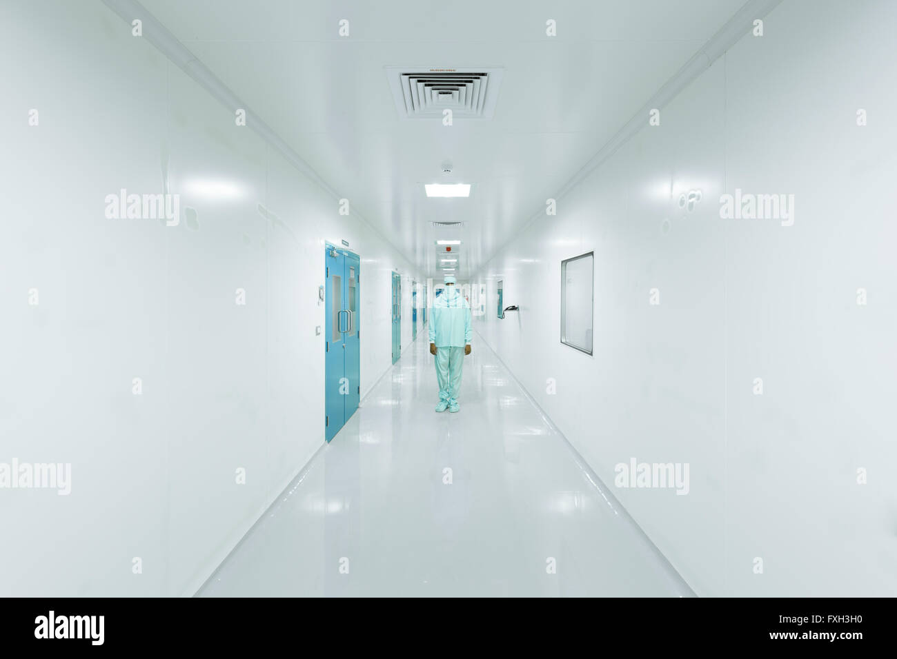 Voce maschile vestito in uniforme di laboratorio in piedi nel centro del corridoio Foto Stock