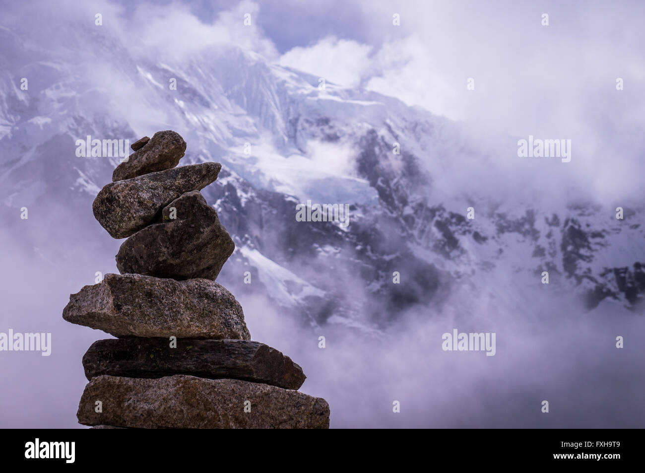 Cusco, Perù in ottobre 2015: una pila di rocce di fronte ad una montagna ricoperta di neve. Pila di rocce sono spesso utilizzate come marcatori di modo fo Foto Stock