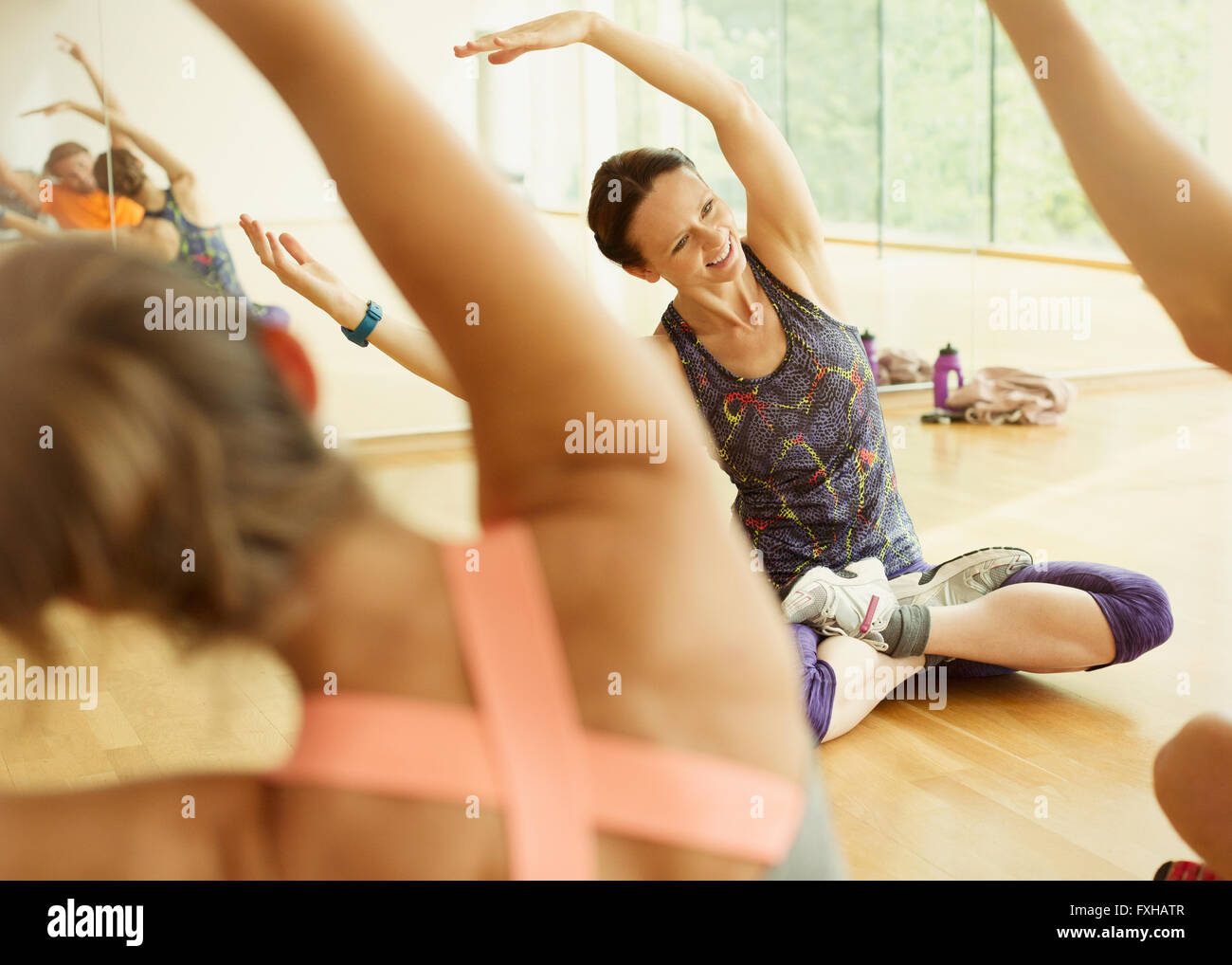 Sorridente istruttore di fitness leader di classe di esercizio di bracci di estensione Foto Stock