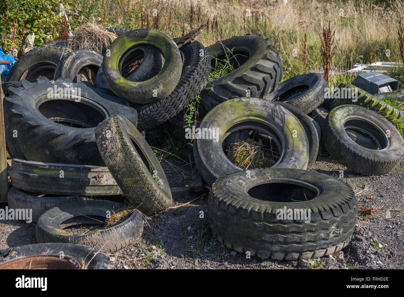 Varietà di vecchia auto scartato, il trattore e i pneumatici autocarro a sinistra in un cortile Foto Stock