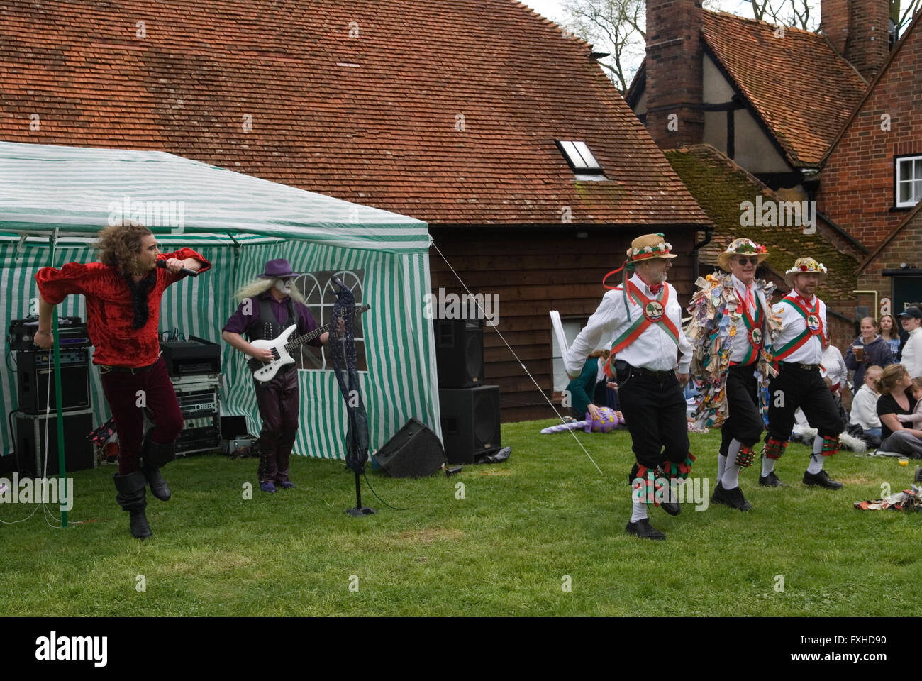 In cerca di attenzione, stile musicale contrastante, Morris Dancing e a Glam Rock Band suonano contemporaneamente. Pub Garden 1° maggio festa del villaggio. Il giardino del pub Perch and Pike. South Stoke Berkshire, Inghilterra anni '2006 2000 UK HOMER SYKES Foto Stock