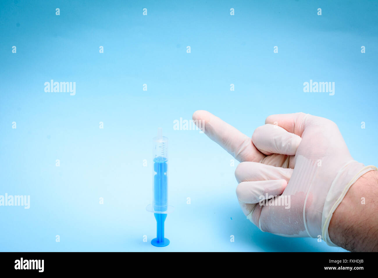 Mano nel guanto di medici su sfondo blu Foto Stock