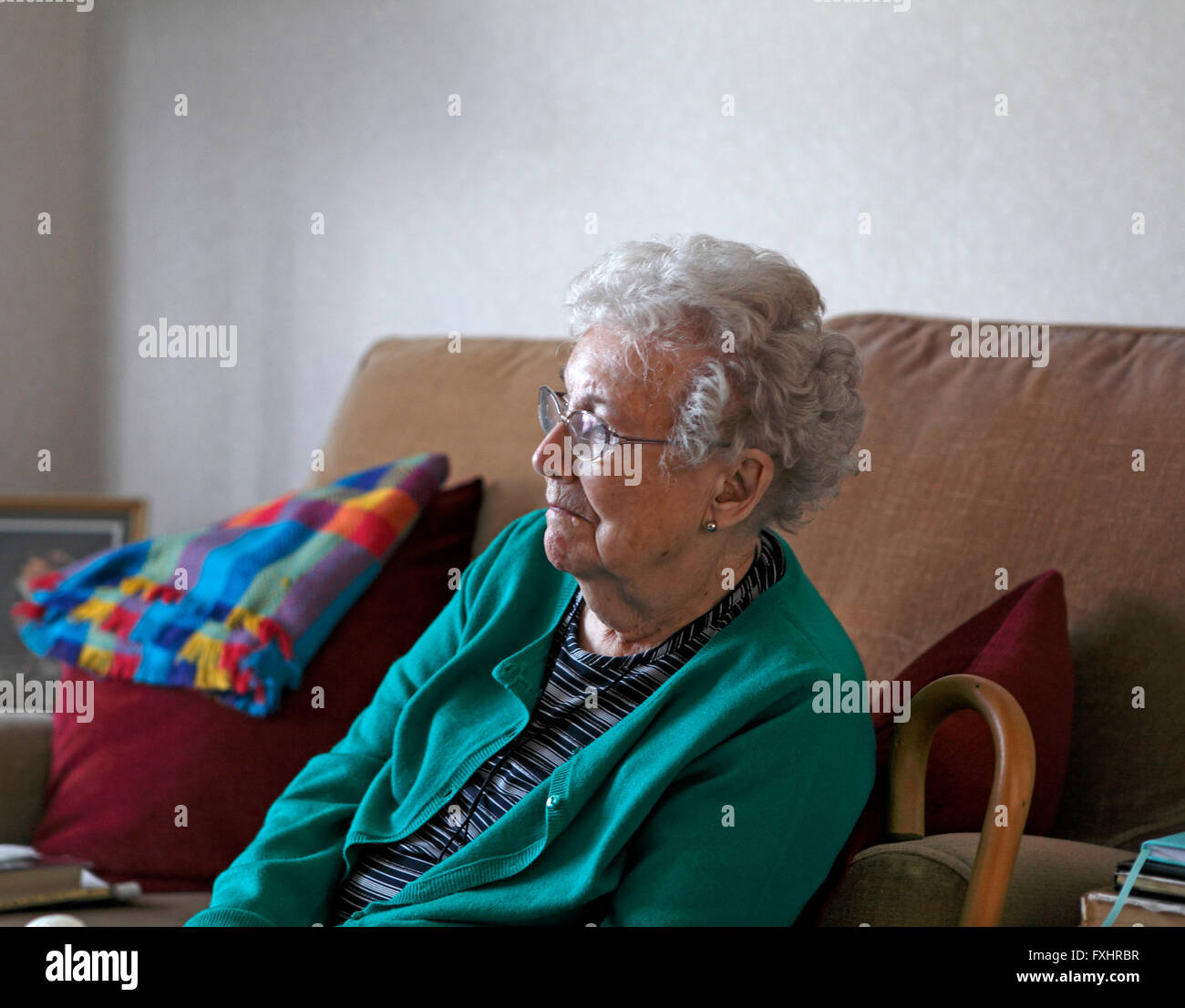 Vecchia signora seduta da sola nella sua casa Foto Stock