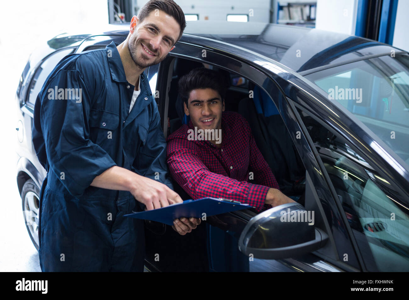 Felice meccanico e il cliente mentre si tiene un preventivo Foto Stock