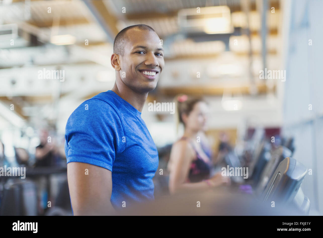 Ritratto uomo sorridente sul tapis roulant in palestra Foto Stock