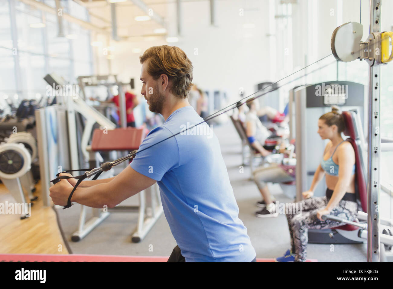 L'uomo utilizzando il cavo attrezzature per esercizi in palestra Foto Stock