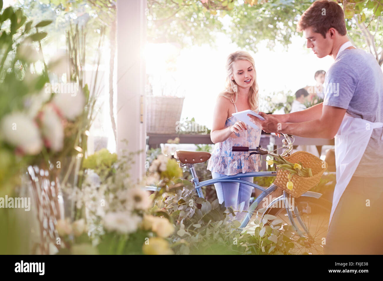 Fioraio con tavoletta digitale a parlare con il cliente con la bicicletta Foto Stock