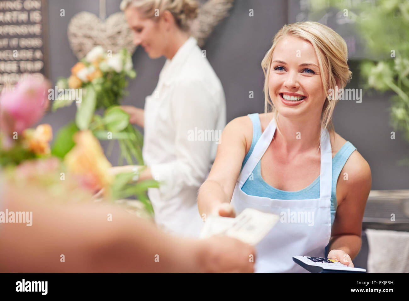 Fiorista sorridente di essere pagato dal cliente in negozio di fiori Foto Stock