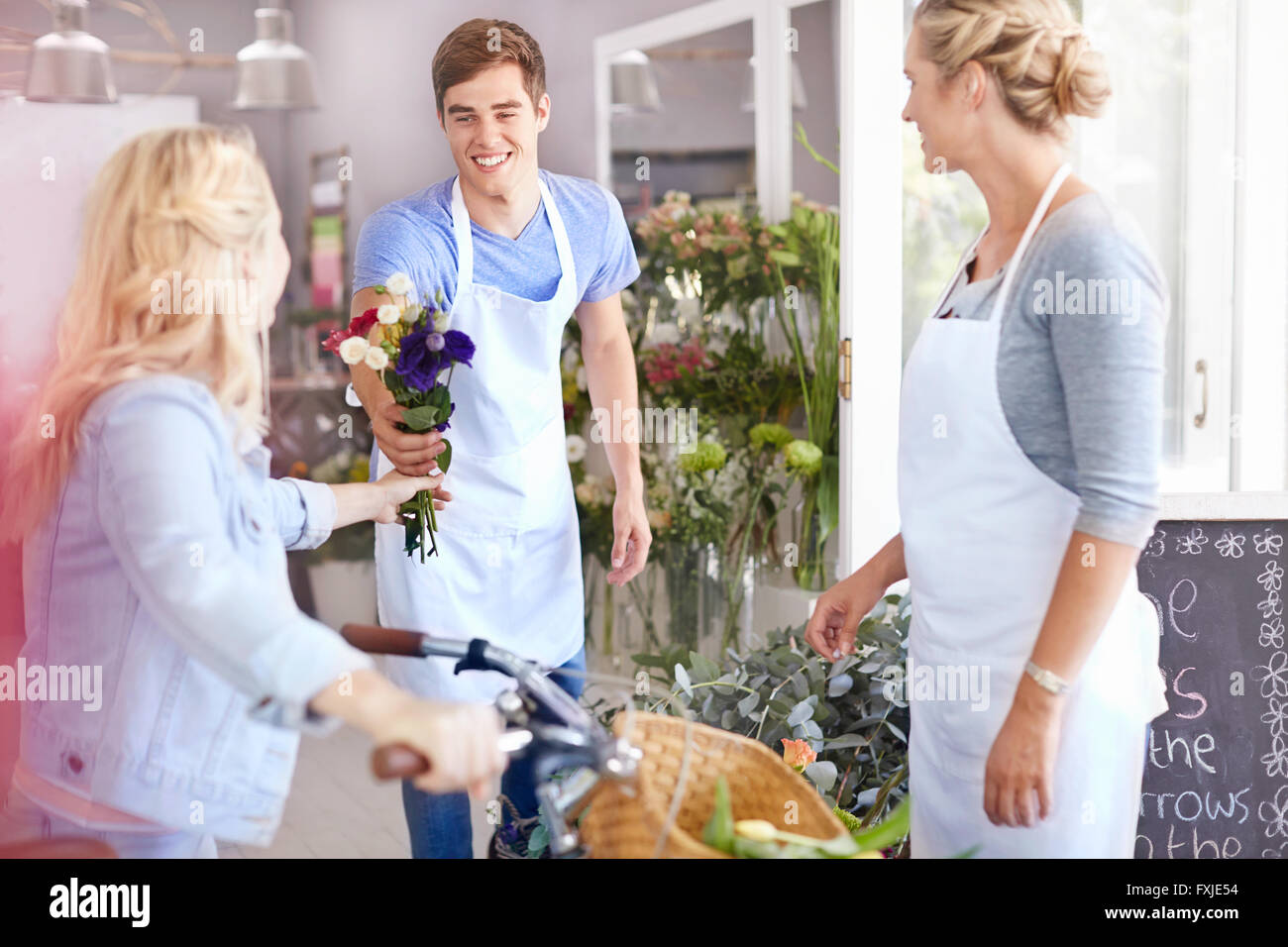 Fioraio dando bouquet del cliente in negozio di fiori Foto Stock