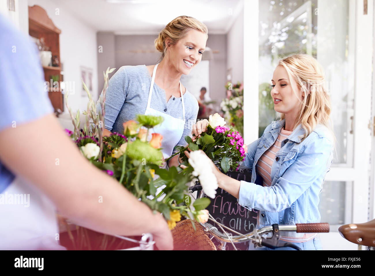 Fioraio aiutando donna ritirare fiori nel negozio di fiori Foto Stock