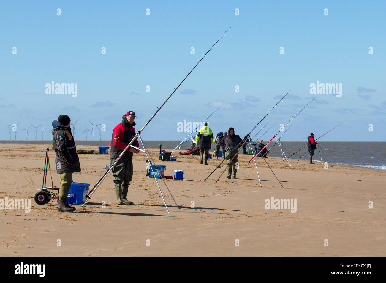 New Brighton, Wirral, Merseyside Regno Unito alle canne da pesca in cui i pescatori di mare approfittare del sole di primavera al pesce di mare nel fiume Mersey. In questa posizione del ciclo della marea è bassa estrema acqua dando accesso per il pescatore per le piscine più profonde e canali nell'estuario. Foto Stock