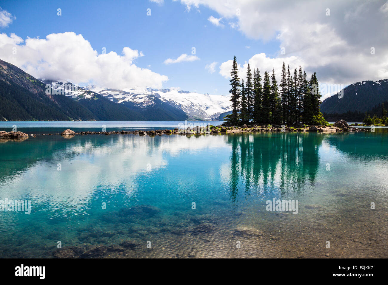 Tranquilla e chiare acque del lago Garibaldi riflettono gli alberi e le montagne in sfumature di blu e verde smeraldo e la bottiglia e verde Foto Stock