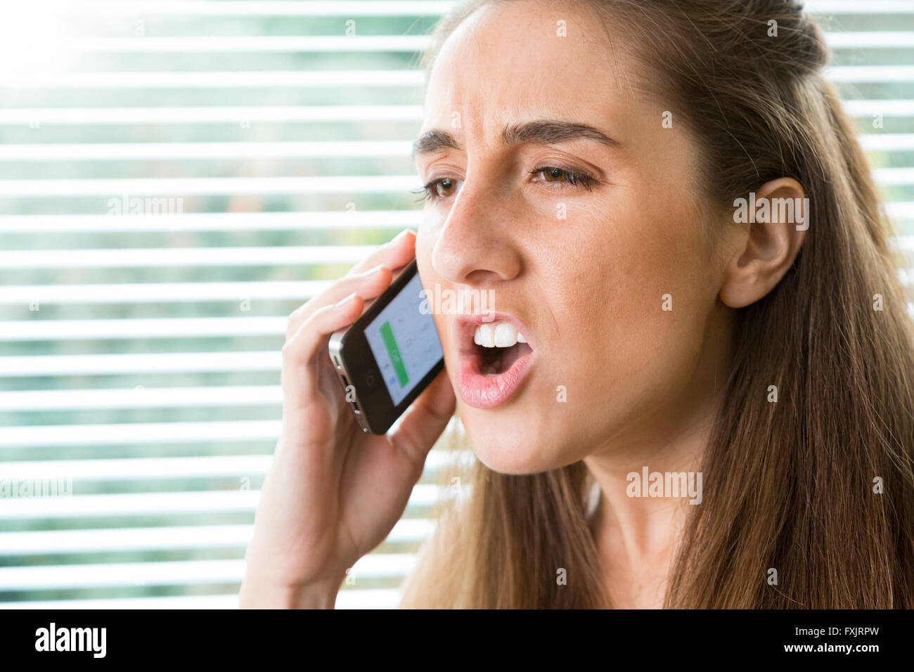 Giovane donna grida sul telefono cellulare Foto Stock
