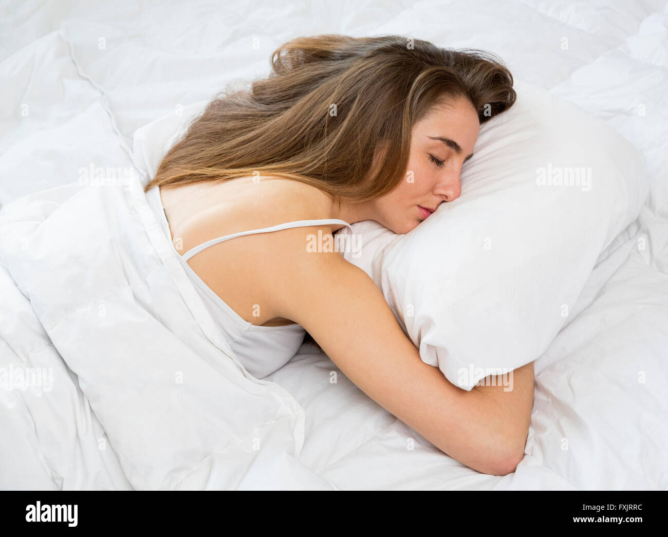 Giovane donna che dorme nel letto Foto Stock