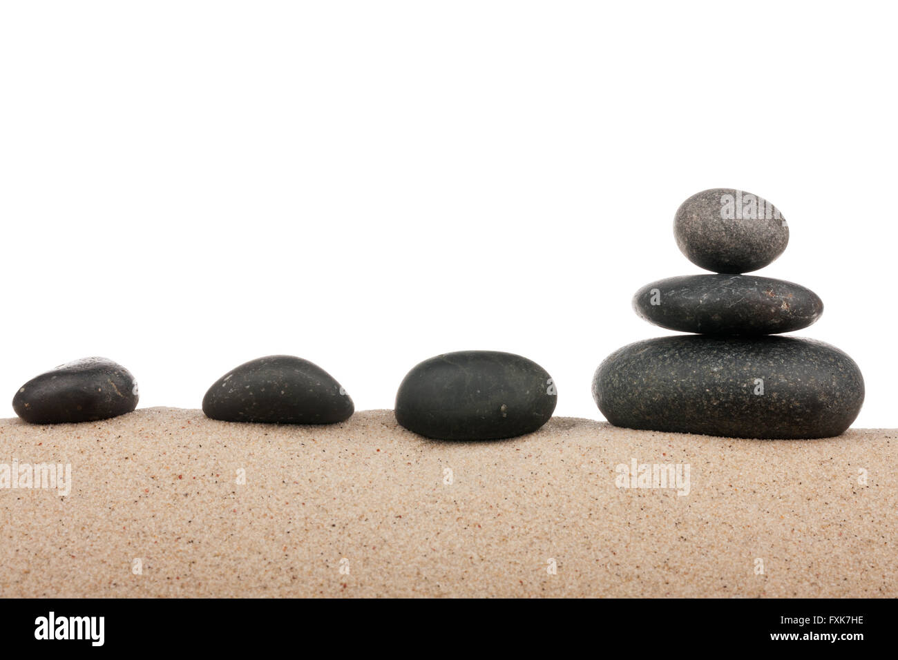 Zen piramide di pietre sulla spiaggia di sabbia, la meditazione, la concentrazione, relax e armonia, equilibrio, isolato su sfondo bianco Foto Stock