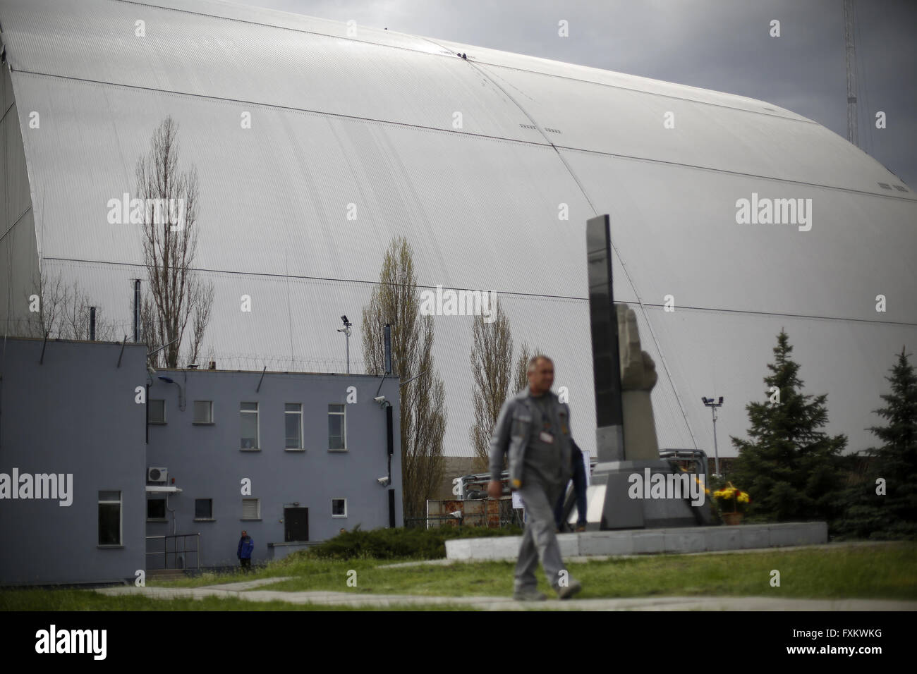 Aprile 16, 2016 - Lavoratore passeggiate passato Chernobyl nuovo confinamento sicuro struttura (NSC) in costruzione, un arco che riguarderà la costruzione del reattore numero 4 una volta posto su Chernobyl centrale nucleare, il 16 aprile 2016. Il nuovo confinamento sicuro struttura è assemblata in due metà ciascuna delle quali comprendente diversi tratti arcuati. Gli ucraini mark 30 anni poiché il mondo peggiore disastro nucleare di Chernobyl pant nucleare in Ucraina. L'esplosione durante i test al reattore numero 4 della centrale di Cernobyl nelle prime ore del 26 aprile 1986 inviata ricadute radioattive in th Foto Stock