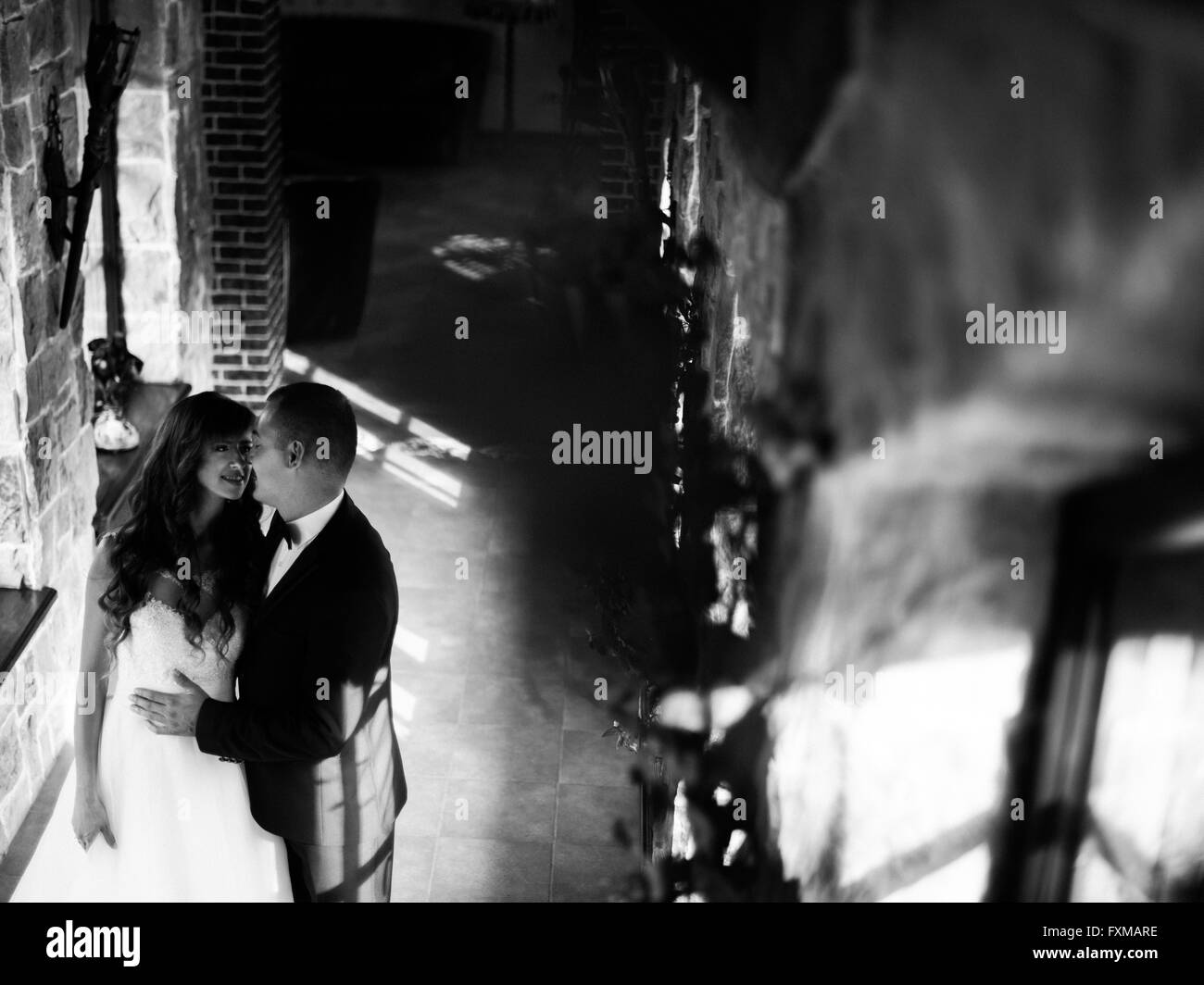 Giovane e bella coppia sposata in piedi dalla finestra abbracciando faccia a faccia Foto Stock