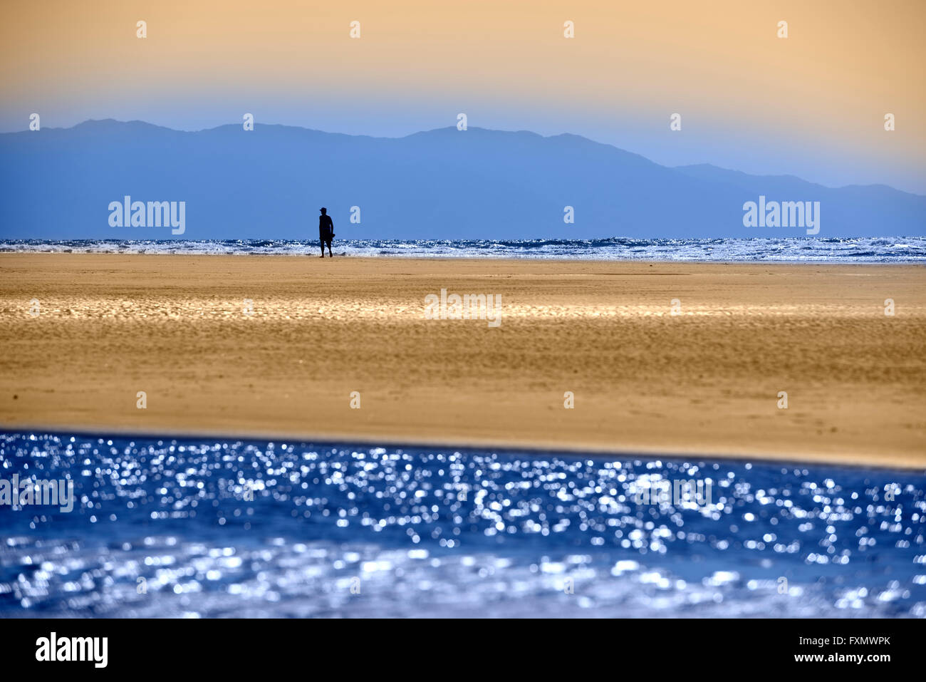 Singolo uomo sulla spiaggia messicana con colorati oceano Pacifico e Sierra Madre Mountains Nuevo Vallarta Messico blu e arancione Foto Stock