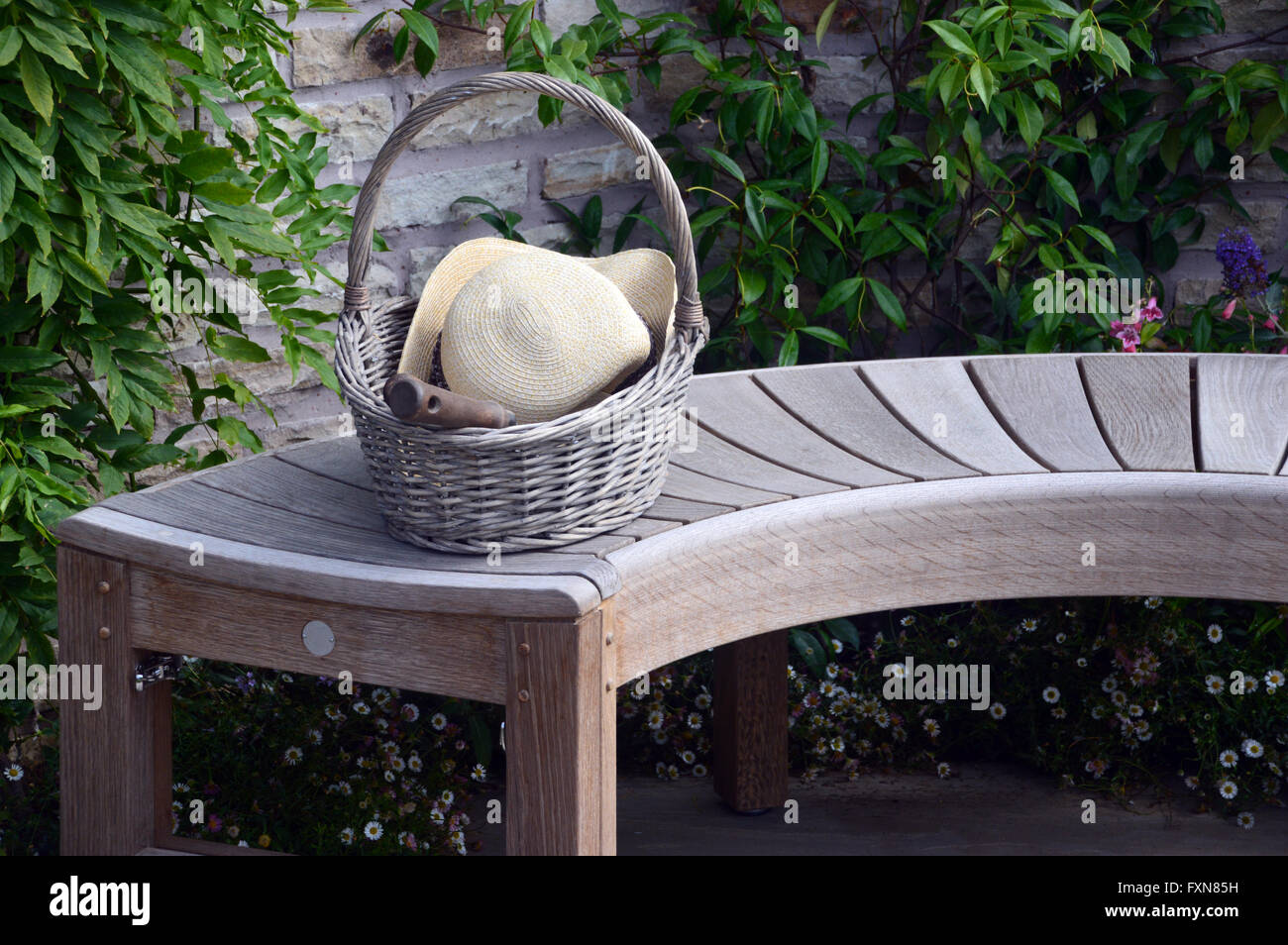 Curvo banco in legno con cesto in vimini, cappello e frattazzo su Display in autunno Southport Flower Show. Lancashire Regno Unito. Foto Stock