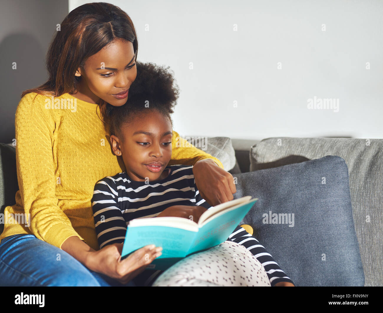 Mom figlia di insegnamento per leggere in ambiente rilassato Foto Stock