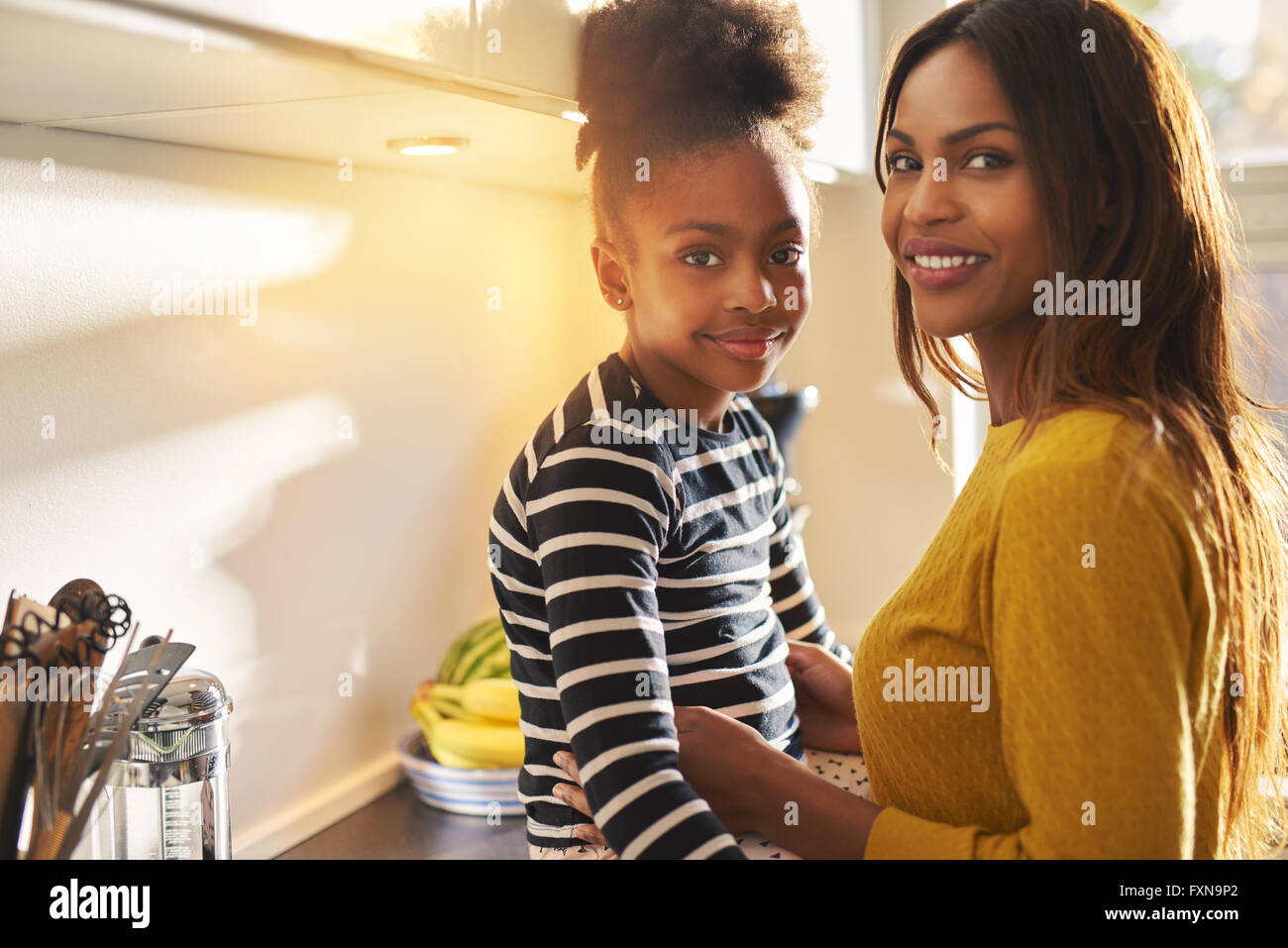 Bella black mamma e figlia a casa sorridente alla fotocamera, luce calda Foto Stock