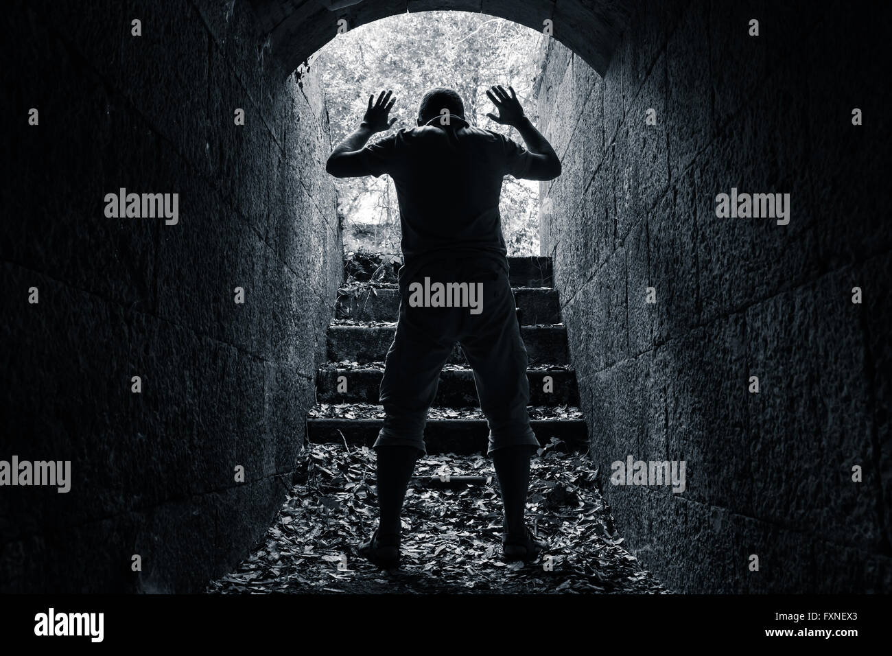 L'uomo lascia scuro tunnel in pietra con le mani alzate, concetto di riscatto foto in bianco e nero Foto Stock