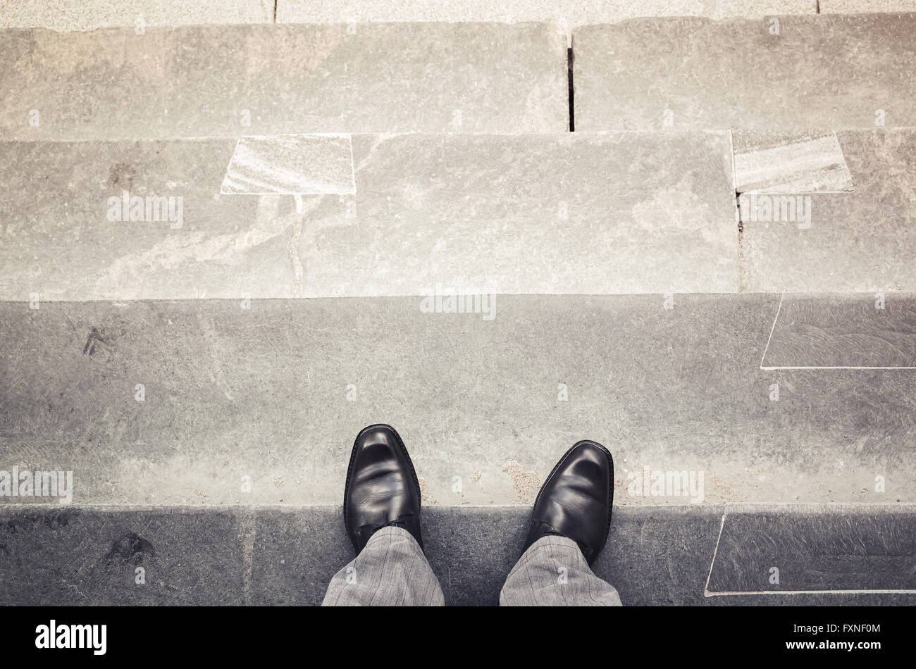 Piedini maschio nel nuovo splendente nero scarpe in pelle stand all'aperto sulle scale di pietra prospettiva in prima persona, vintage la correzione delle tonalità foto fil Foto Stock