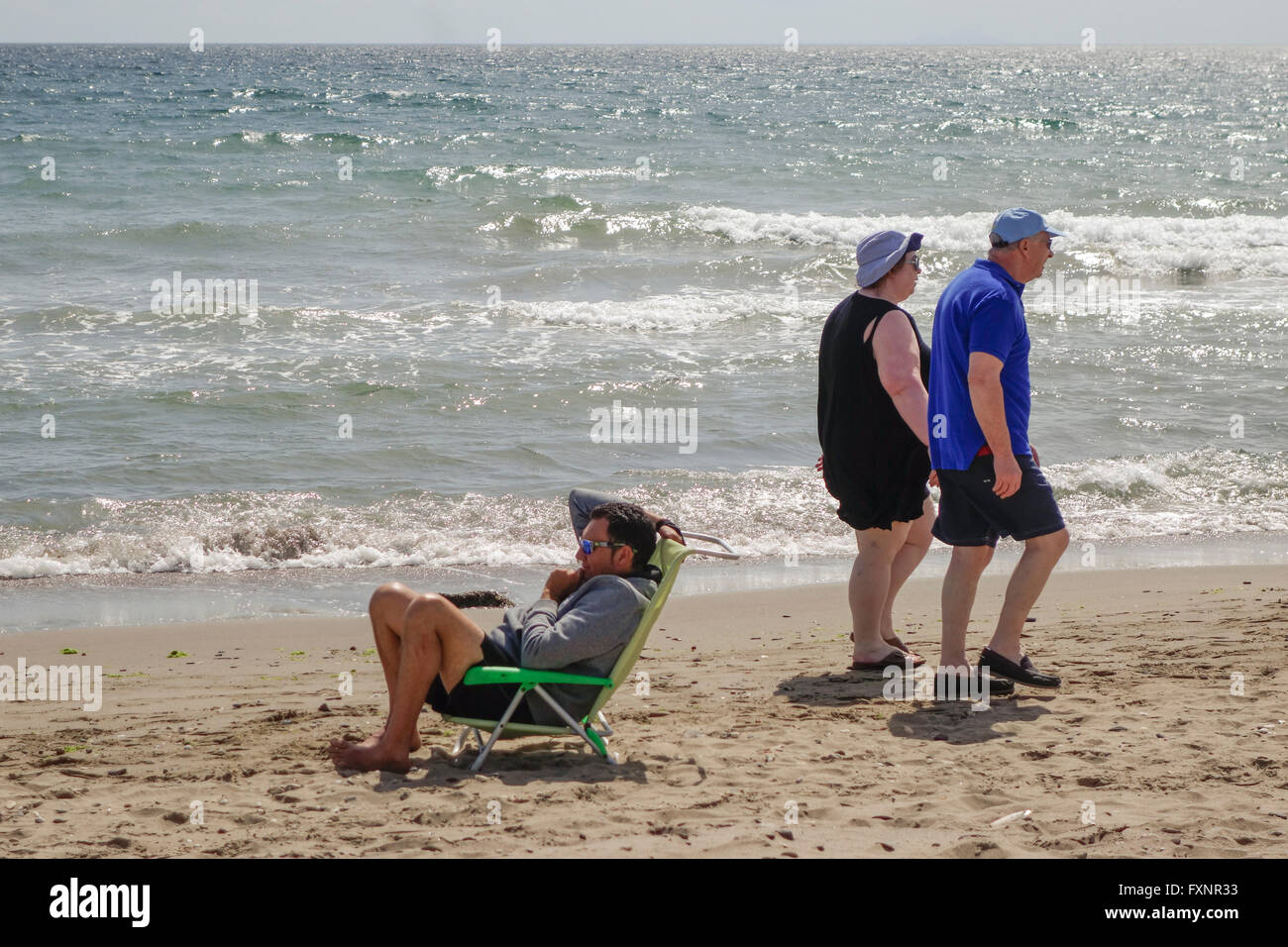 Coppia di anziani facendo una passeggiata lungo la spiaggia in Spagna durante la offuscato meteo. Andalusia, Spagna. Foto Stock