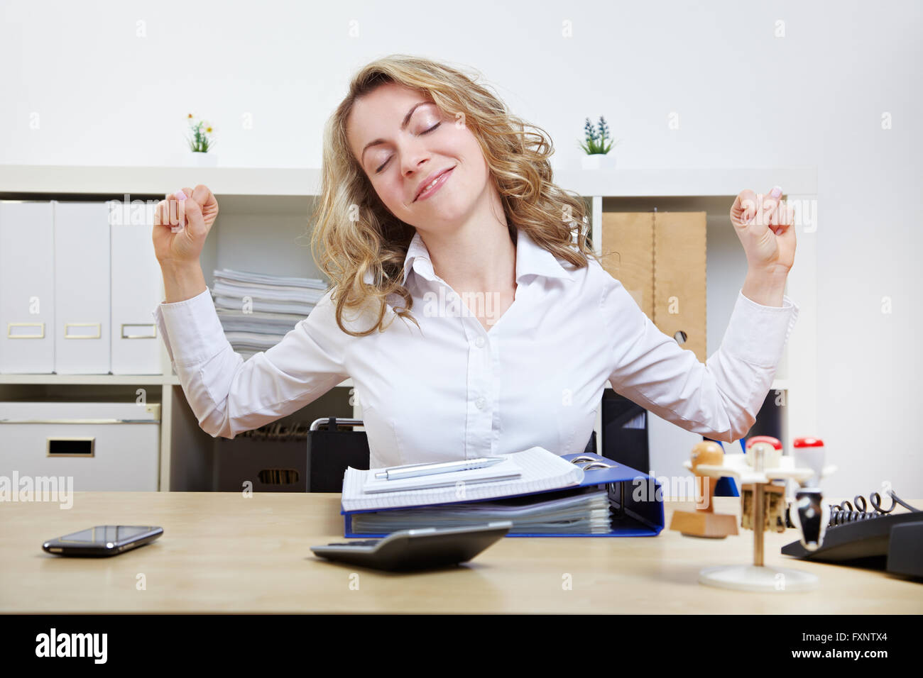 Business donna alla sua scrivania stretching i suoi muscoli Foto Stock