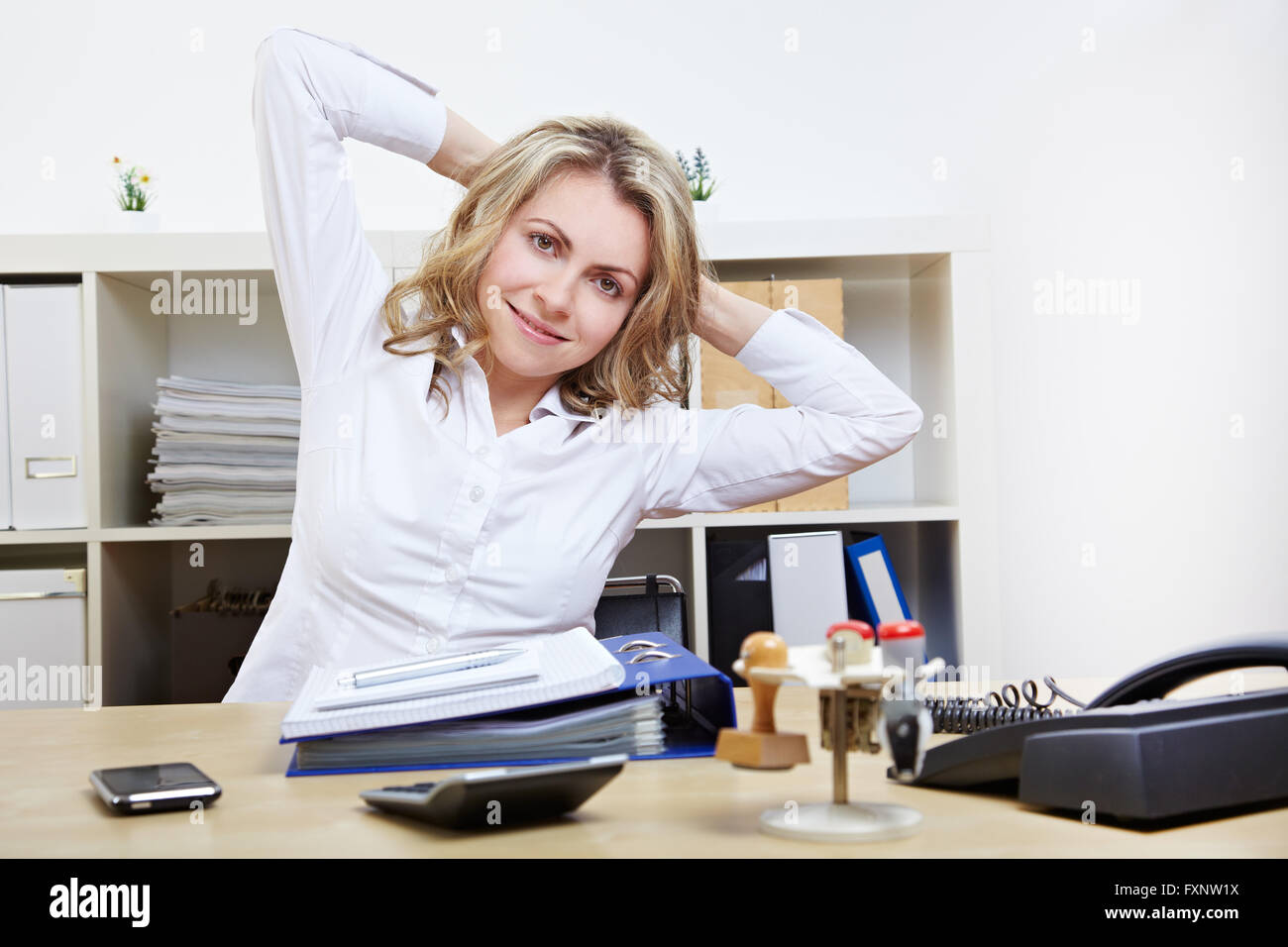 Happy business donna facendo esercizi per la schiena al lavoro nel suo ufficio Foto Stock