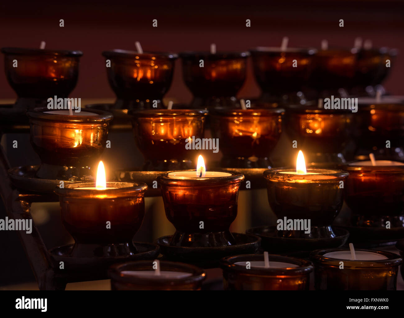 Tre illuminati candele votive Foto Stock