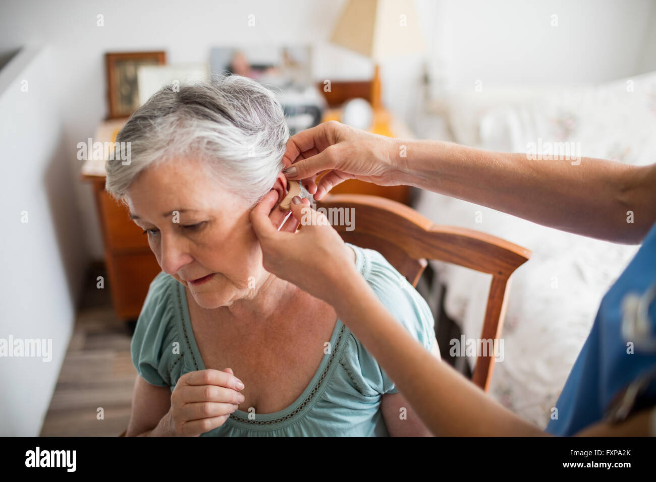 L'infermiera mettendo hearing aid a un senior donna Foto Stock