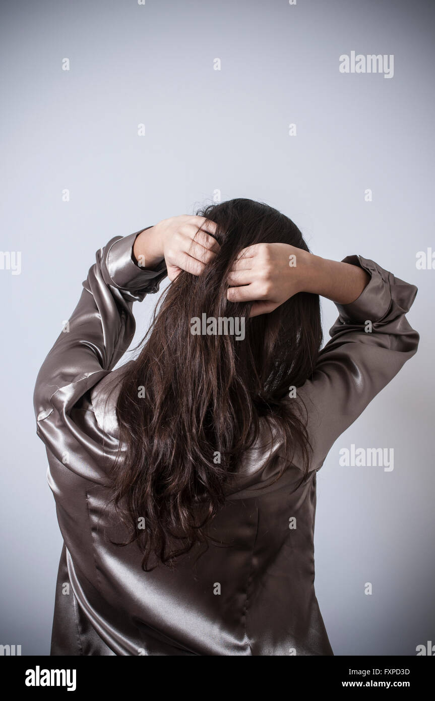 Vista posteriore di una giovane donna le mani sulla testa Foto Stock