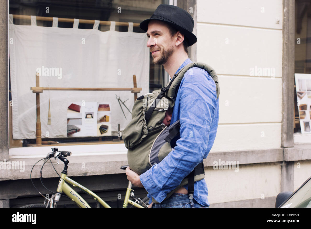 Uomo fuori e circa nella città con il bambino in carrier Foto Stock