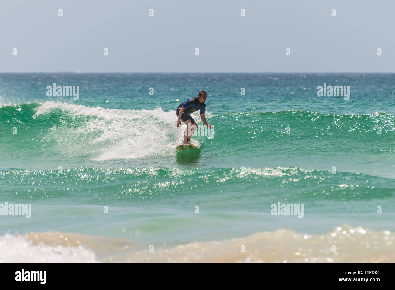 Un uomo che cavalca il suo surfboard verso la riva. A sette miglia dal centro di Sydney, nota Manly Beach Foto Stock