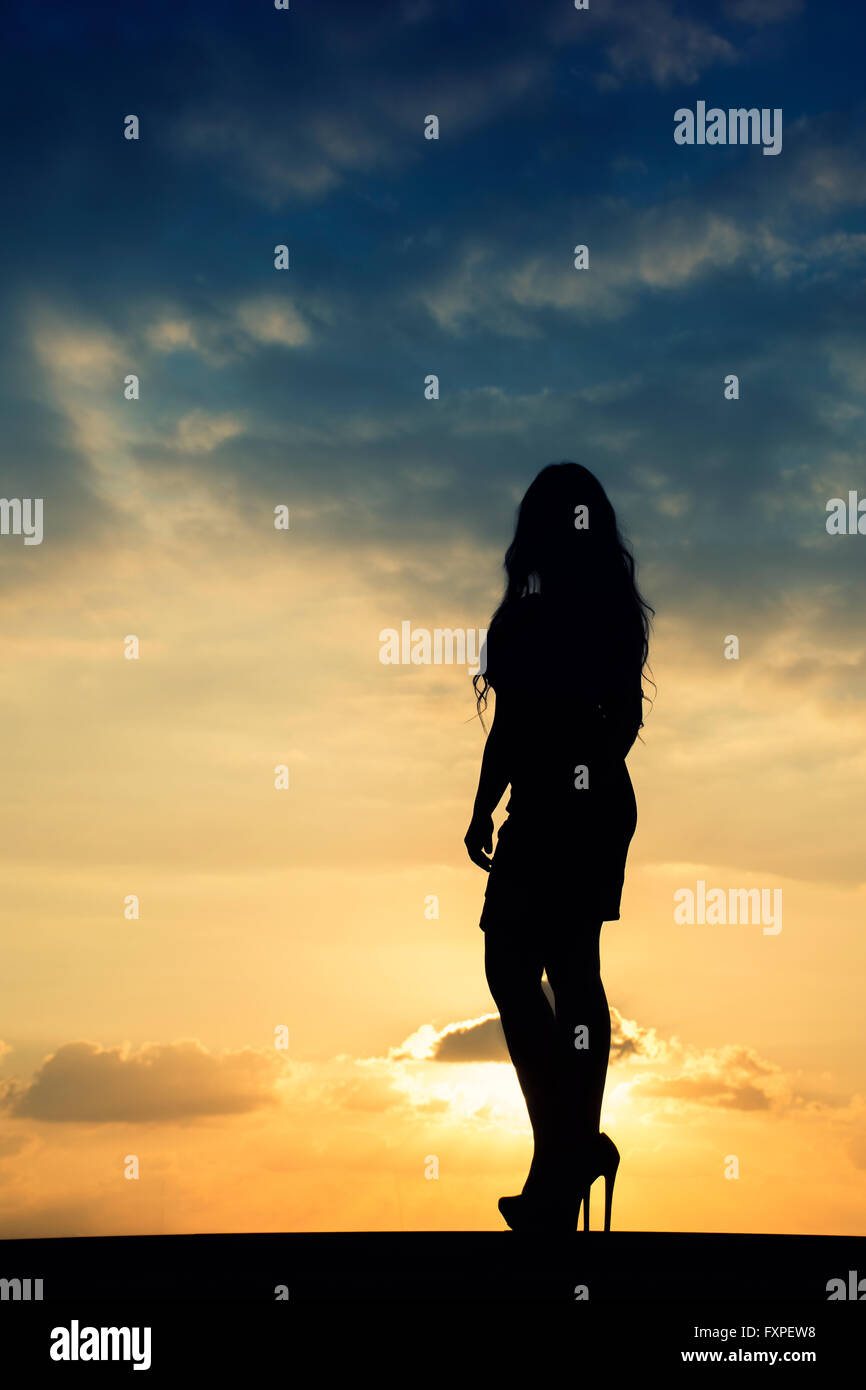 Lunghezza completa silhouette di una donna in piedi contro un tramonto spettacolare Foto Stock