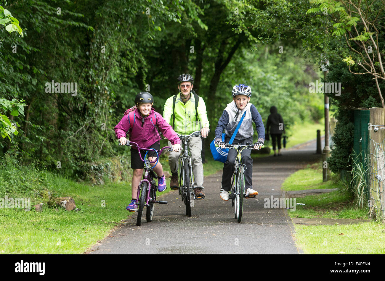 I bambini in modo sicuro il ciclismo a scuola con la supervisione di un adulto su pathways Foto Stock