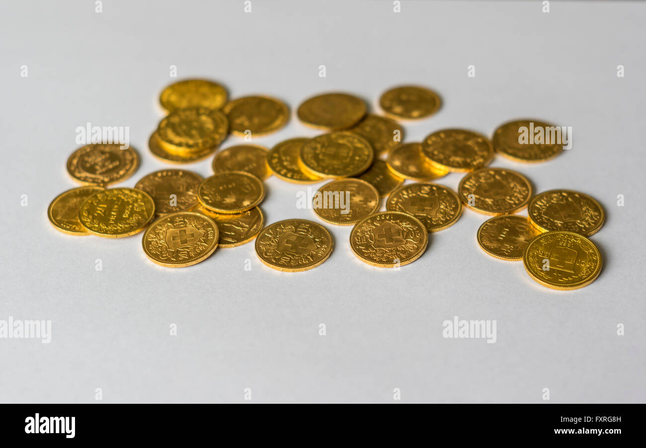 Decine di monete d'oro, per la maggior parte del XIX secolo 20 monete in franchi provenienti dalla Svizzera, impilate su sfondo bianco Foto Stock