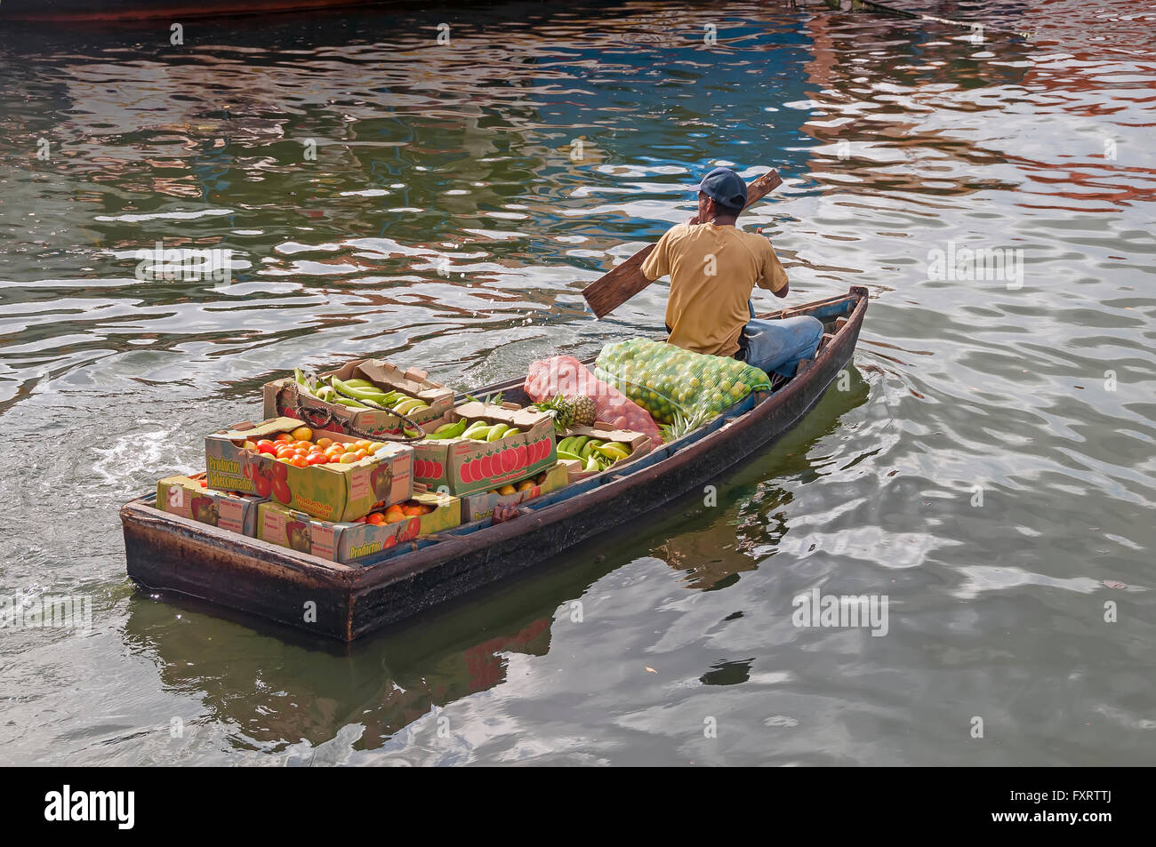 L'uomo pagaie skiff caricato con frutti provenienti dal mercato galleggiante, Willemstad Curacao Foto Stock