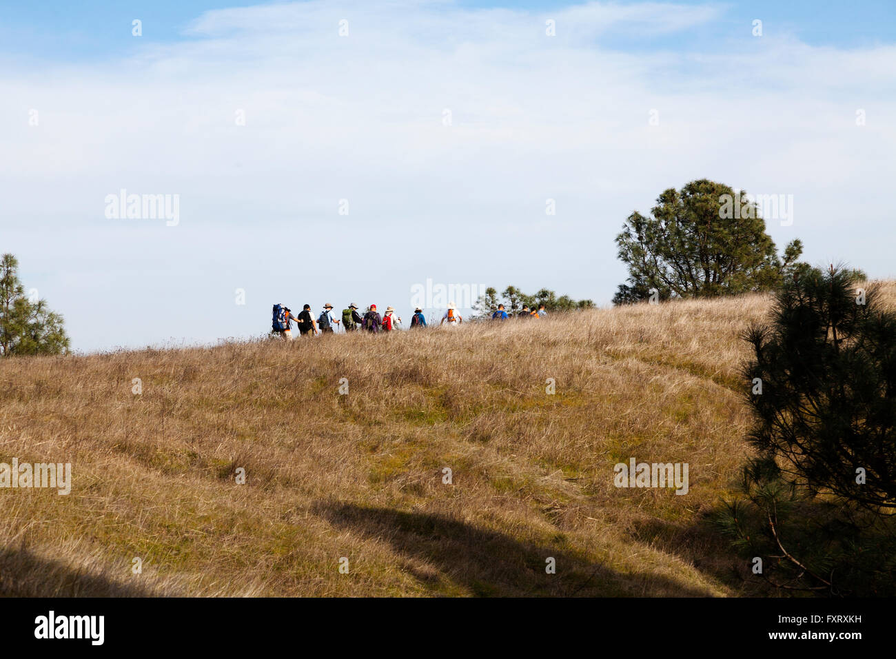 Linea di escursionisti collina ascendente contro Sky Foto Stock