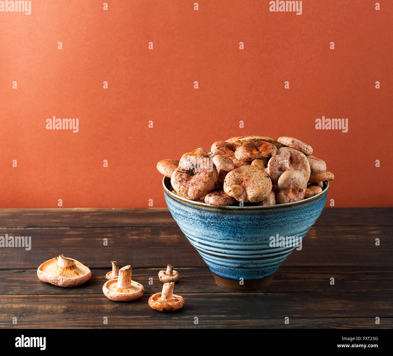 I funghi commestibili - Zafferano cappuccio di latte nella tazza di ceramica su rustiche in legno marrone tabella. L'immagine verticale con copia spazio. Foto Stock