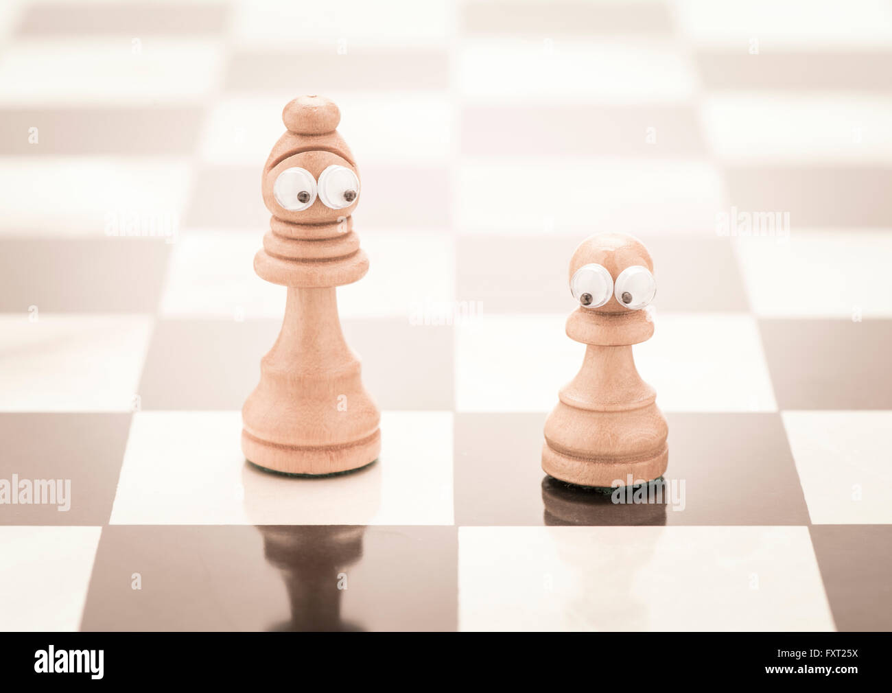 Pezzi di scacchi con gli occhi di un alto e uno piccolo Foto Stock